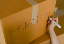 A person labeling a box of fragile items