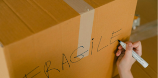 A person labeling a box of fragile items