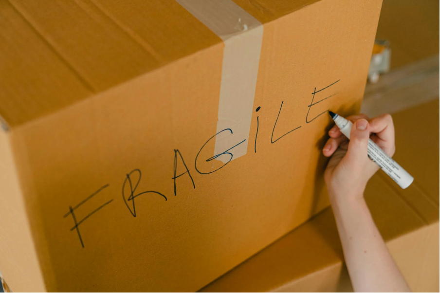 A person labeling a box of fragile items